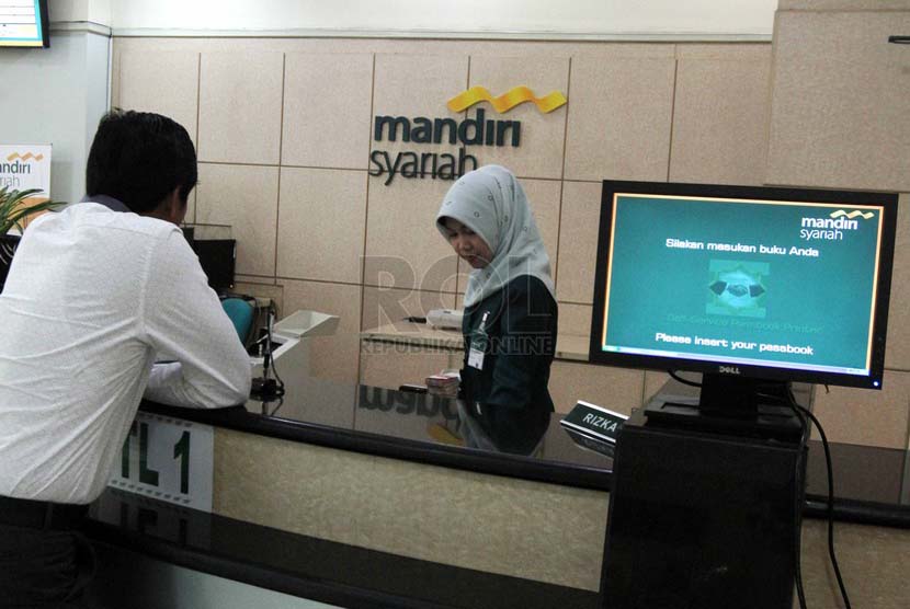 Petugas menghitung uang nasabah di banking hall salah satu kantor cabang Bank Syariah Mandiri, Jakarta, Jumat (4/7).  (Republika/Adhi Wicaksono)