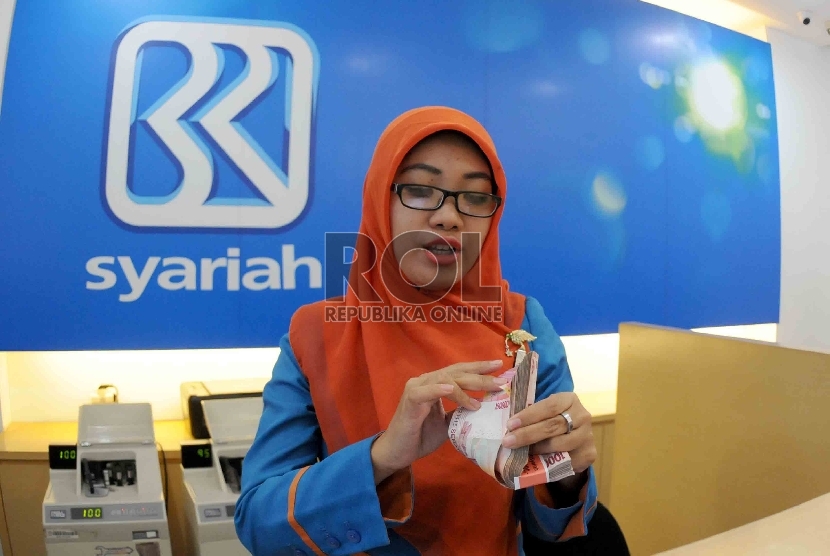  Petugas menghitung uang nasabah di salah kantor Bank BRI Syariah, Jakarta, Kamis (20/8). 
