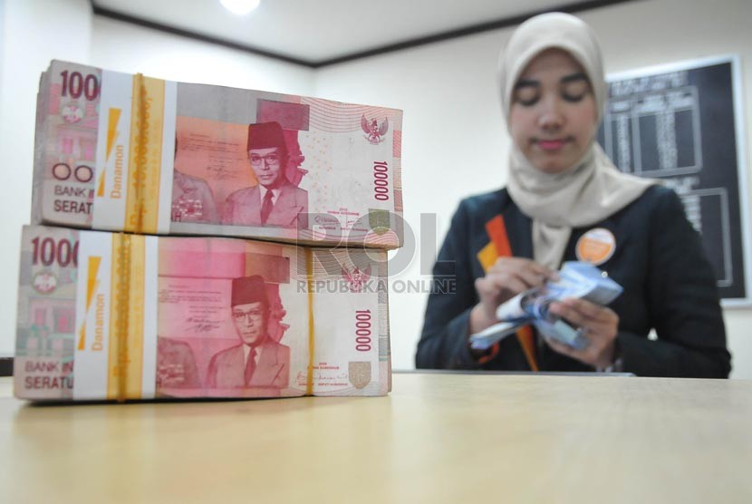 Petugas menghitung uang nasabah di salah satu kantor cabang Bank Danamon Syariah di Jakarta, Jumat (22/8).(Prayogi/Republika)