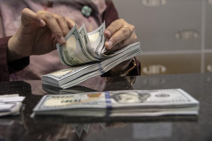 Petugas menghitung uang pecahan dolar AS di gerai penukaran mata uang asing VIP. Dolar AS menguat secara signifikan terhadap sekeranjang mata uang utama lainnya pada akhir perdagangan Kamis (27/7).