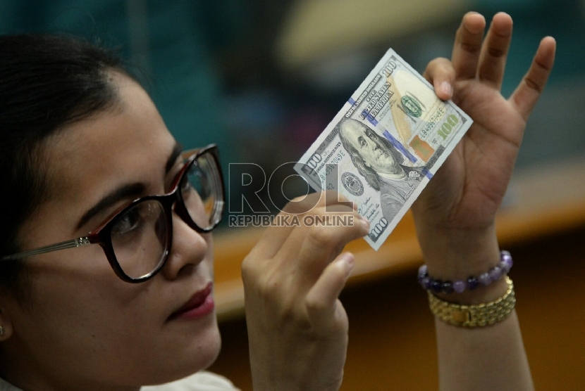 Petugas menghitung uang pecahan Dolar AS di salah satu tempat penukaran uang, Jakarta, Senin (2/2).(Republika/Prayogi)