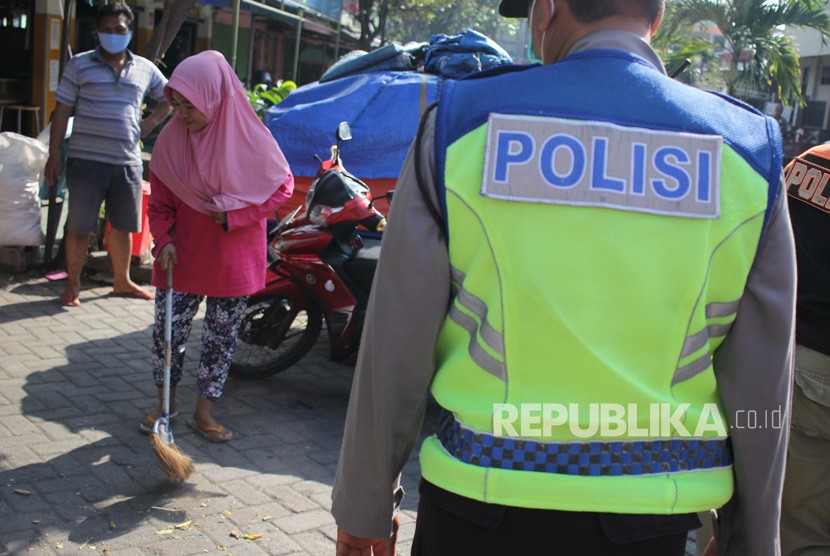 Petugas menghukum warga yang tidak memakai masker untuk menyapu jalan saat razia di Pasar Setro, Surabaya, Jawa Timur, Rabu (8/7/2020). Tindakan itu guna mendisiplinkan warga untuk patuh terhadap protokol kesehatan pencegahan penularan COVID-19. 