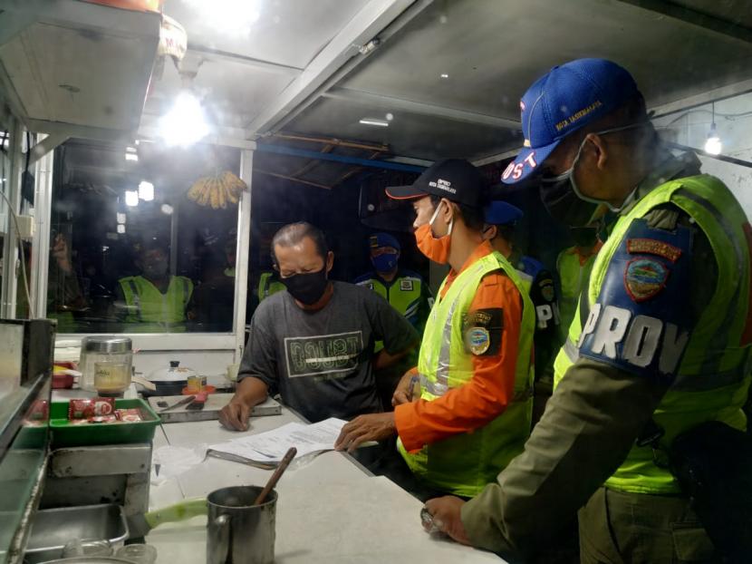 Petugas mengingatkan para pelaku usaha di kawasan pusat pertokoan Jalan KHZ Mustofa, Kota Tasikmalaya, terkait pembatasan kegiatan pada malam hari, Kamis (1/10). 