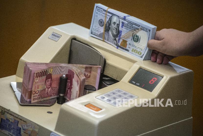 Petugas mengitung uang rupiah di salah satu gerai penukaran uang asing di Jakarta. kekhawatiran penyebaran virus Corona juga melemahkan mata uang regional Asia