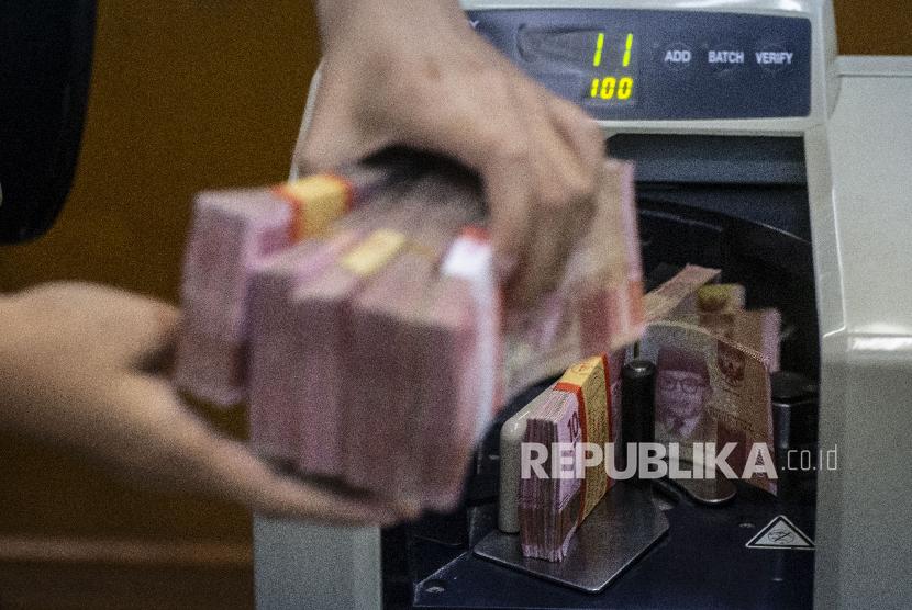 Petugas mengitung uang rupiah di salah satu gerai penukaran uang asing di Jakarta, Rabu (27/11). BI tingkatkan intensitas intervensi di pasar keuangan yang disebut tripel intervensi.