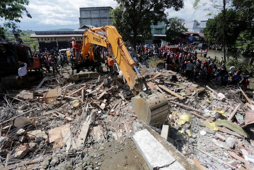 Petugas mengoperasikan alat berat untuk mencari korban di salah satu bangunan yang runtuh akibat gempa 6.5 SR, di Desa Lueng Putu, perbatasan Pidie-Pidie Jaya, Aceh, Rabu (7/12).