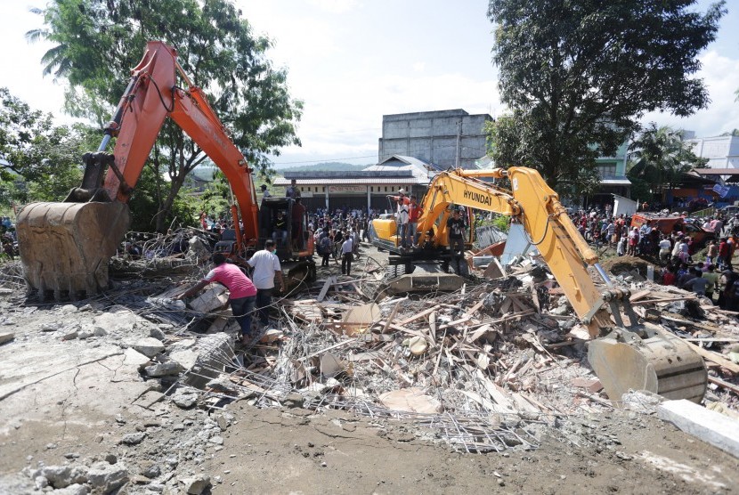 Petugas mengoperasikan alat berat untuk mencari korban di salah satu bangunan yang runtuh akibat gempa 6.5 SR, di Desa Lueng Putu, perbatasan Pidie-Pidie Jaya, Aceh, Rabu (7/12).