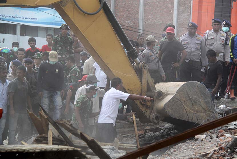 Petugas mengoperasikan alat berat untuk mencari korban yang tertimpa reruntuhan bangunan rumah toko (ruko) akibat gempa di Desa Ulee Glee, Kecamatan Bandar Dua, Kabupaten Pidie Jaya, Aceh, Rabu (7/12). 