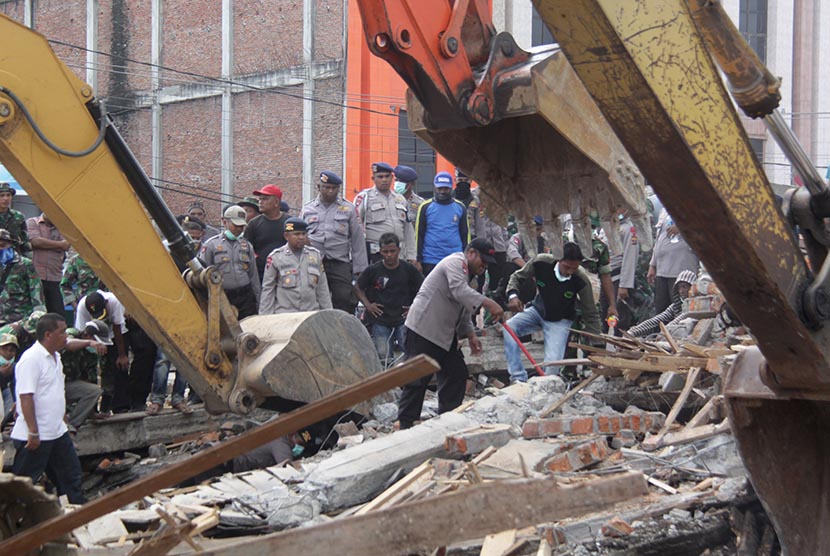 Petugas mengoperasikan alat berat untuk mencari korban yang tertimpa reruntuhan bangunan rumah toko (ruko) akibat gempa di Desa Ulee Glee, Kecamatan Bandar Dua, Kabupaten Pidie Jaya, Aceh, Rabu (7/12). 