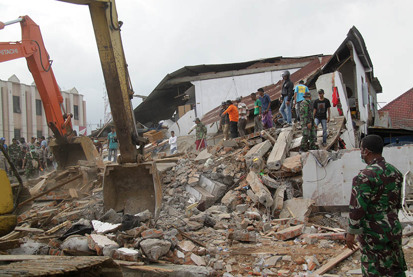 Petugas mengoperasikan alat berat untuk mencari korban yang tertimpa reruntuhan bangunan rumah toko (ruko) akibat gempa di Desa Ulee Glee, Kecamatan Bandar Dua, Kabupaten Pidie Jaya, Aceh, Rabu (7/12). 