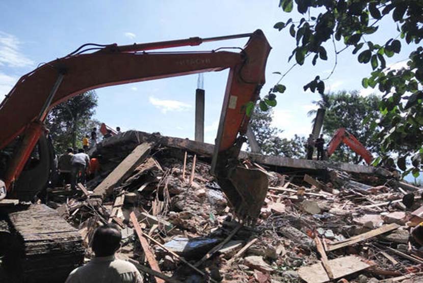 Petugas mengoperasikan alat berat untuk mencari korban yang tertimpa reruntuhan bangunan di Kabupaten Pidie Jaya, Aceh, Rabu (7/12). 