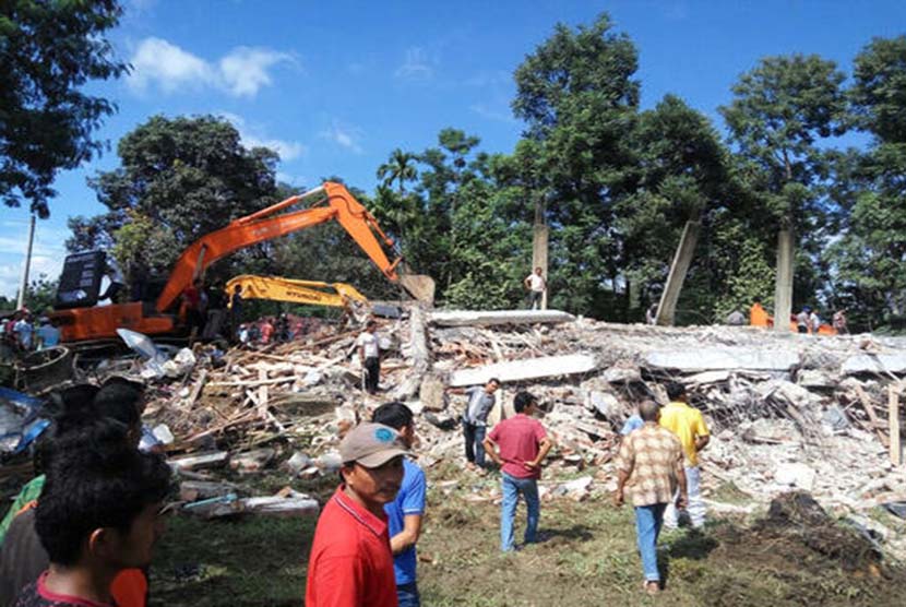 Petugas mengoperasikan alat berat untuk mencari korban yang tertimpa reruntuhan bangunan di Kabupaten Pidie Jaya, Aceh, Rabu (7/12). 