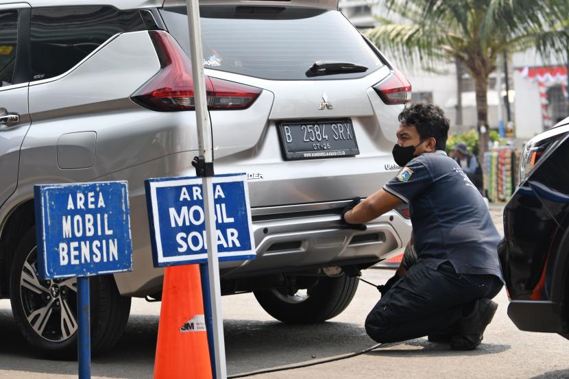 Petugas menguji emisi salah satu mobil milik warga yang melintas di Jalan Kali Besar Barat, Tambora, Jakarta. Pemerintah menyebut pajak kendaraan listrik lebih murah daripada kendaraan hybrid. Hal ini sejalan upaya pemerintah mendorong kebijakan net zero emission, salah satunya pemanfaatan kendaraan listrik berbasis baterai.
