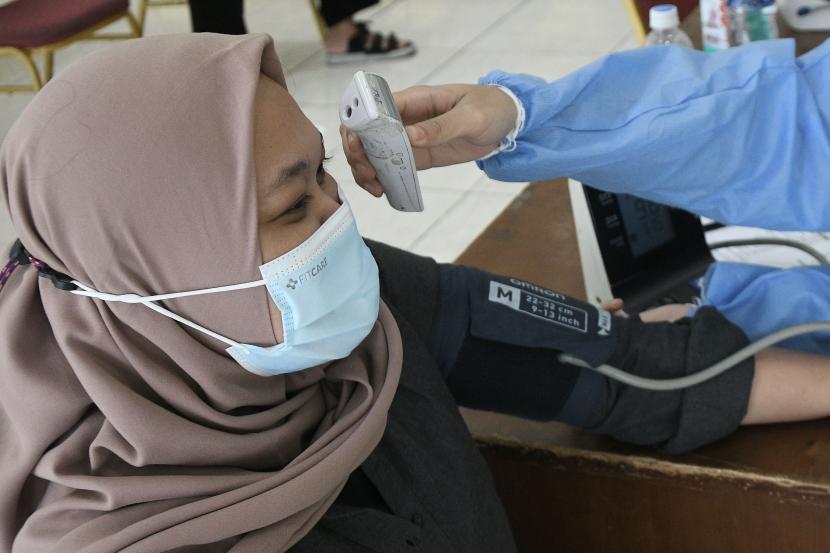 Petugas mengukur suhu tubuh tenaga kesehatan sebelum mengikuti Vaksinasi COVID-19 booster kedua di Gelanggang Remaja Pulogadung, Jakarta Timur, Senin (1/8/2022). Vaksinasi booster kedua yang diadakan 1-5 Agustus tersebut diberikan untuk tenaga kesehatan dengan ketersediaan 150 dosis per hari. Pasien Covid-19 Bertambah 5.869 Orang, Terbanyak dari DKI Jakarta