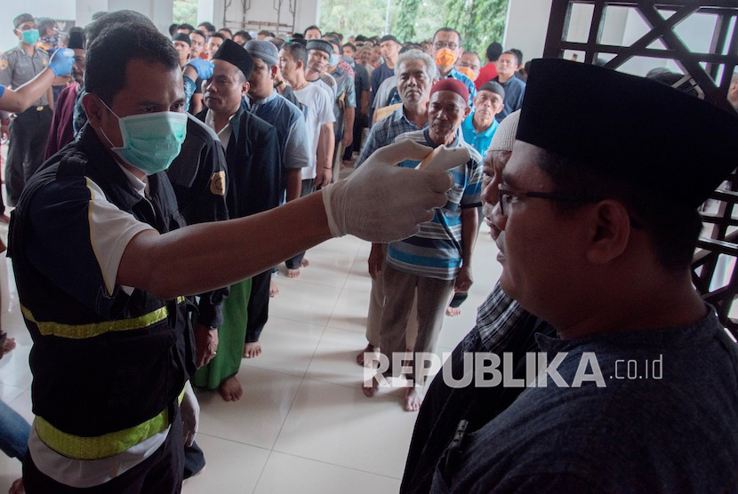 Petugas mengukur suhu tubuh warga sebelum melaksanakan sholat Jumat di masjid Agung Sukabumi, Jawa Barat, Jumat (20/3/2020). 