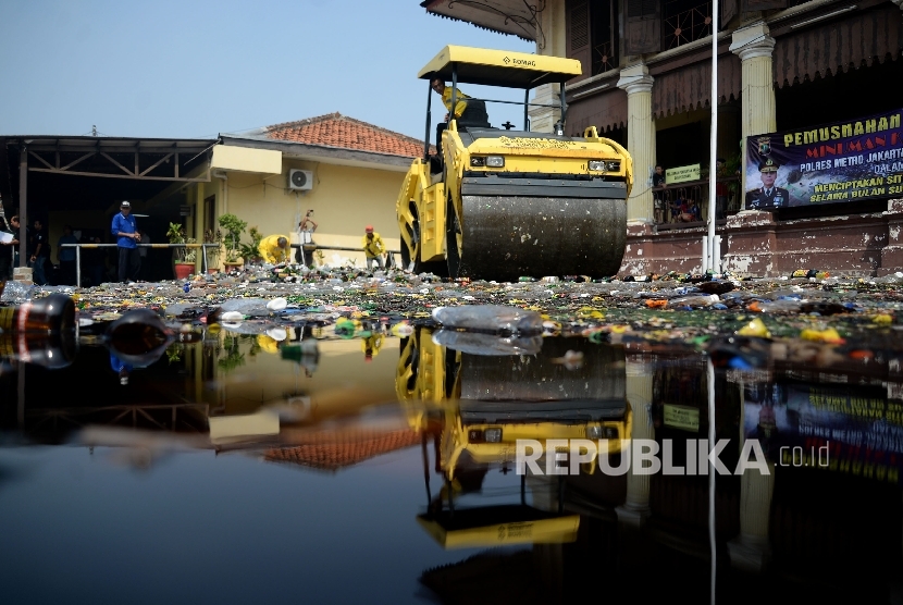Petugas mengunakan alat berat memusnahkan barang bukti minuman keras (miras) di halaman Polsek Palmerah, Jakarta, Selasa (23/5).