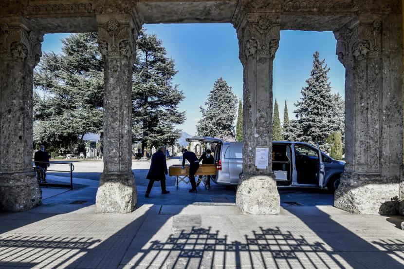 Petugas mengusung peti jenazah di pemakaman Bergamo di Italia Utara, Senin (16/3). Bergamo adalah salah satu yang paling terdampak virus corona di Italia. (Claudio Furlan/LaPresse via AP)