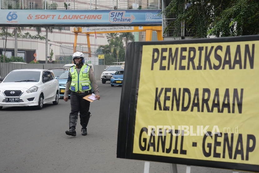 Petugas menilang pengendara mobil yang melanggar aturan pembatasan kendaraan sistem ganjil genap di MH Thamrin, Jakarta Pusat, Selasa (30/8). (Republika/Yasin Habibi)
