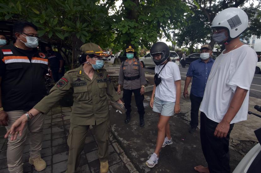 Petugas menindak warga negara asing pelanggar protokol kesehatan dalam Pemberlakuan Pembatasan Kegiatan Masyarakat (PPKM) di Denpasar, Bali.