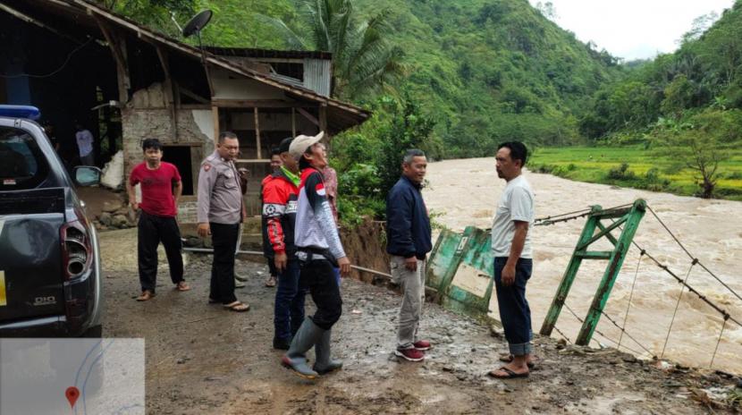 Petugas meninjau lokasi jembatan ambruk di Kampung Padengdeng, Desa Jatisari, Kecamatan Cisompet, Kabupaten Garut, Jumat (2/12/2022). 