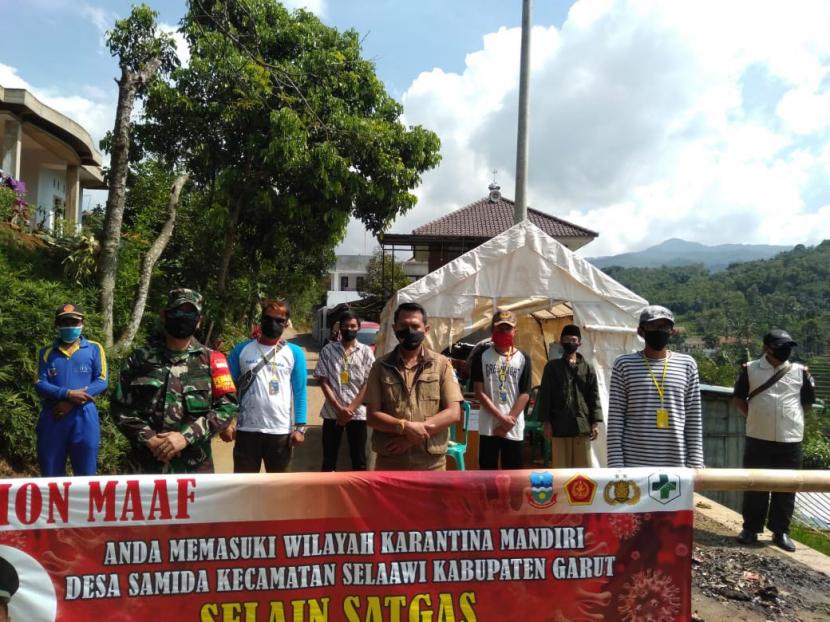 Petugas menjaga perbatasan jalan menuju Kampung Baeud, Desa Samida, Kecamatan Selaawi, Kabupaten Garut, yang melaksanakan karantina mandiri.