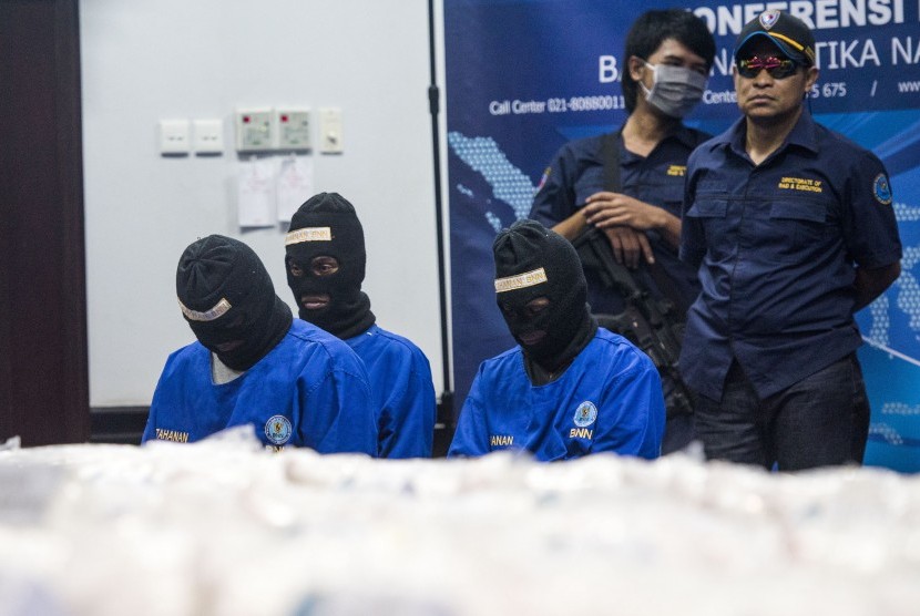 Petugas menjaga tiga tersangka saat gelar barang bukti pengungkapan dan penangkapan peredaran sabu di kantor BNN, Jakarta, Selasa (20/10).