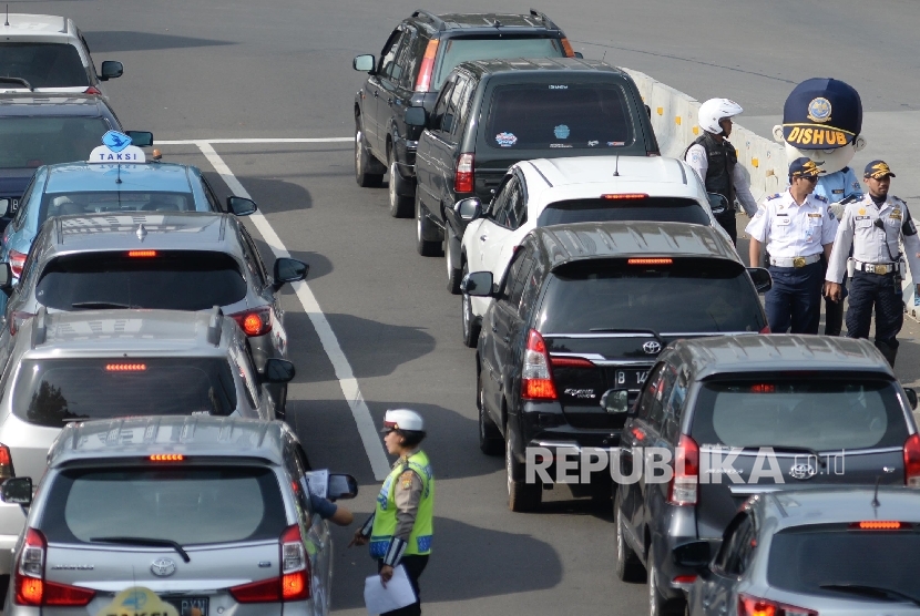 Petugas mensosialisasikan sistem lalu lintas plat ganjil genap kepada pengendara untuk sejumlah jalan protokol pada uji coba sistem tersebut Jalan Medan Merdeka Barat, Jakarta, Rabu (27/7).   (Republika/Yasin Habibi)