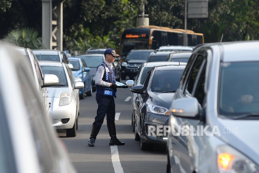 Petugas mensosialisasikan sistem lalu lintas pelat ganjil-genap kepada pengendara untuk sejumlah jalan protokol pada uji coba sistem tersebut Jalan Medan Merdeka Barat, Jakarta, Rabu (27/7). (Republika/Yasin Habibi)