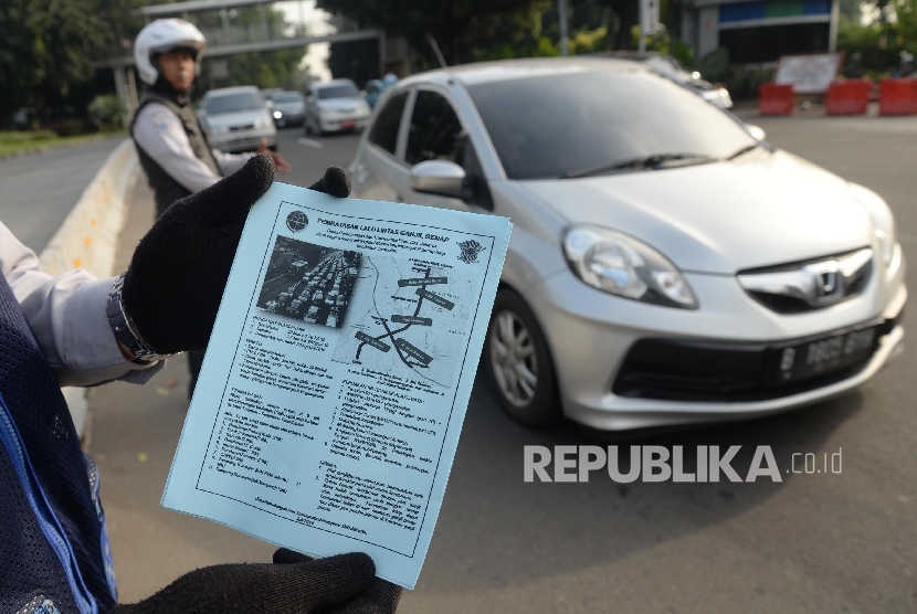 Petugas mensosialisasikan sistem lalu lintas pelat ganjil-genap kepada pengendara untuk sejumlah jalan protokol pada uji coba sistem tersebut Jalan Medan Merdeka Barat, Jakarta, Rabu (27/7). (Republika/Yasin Habibi)