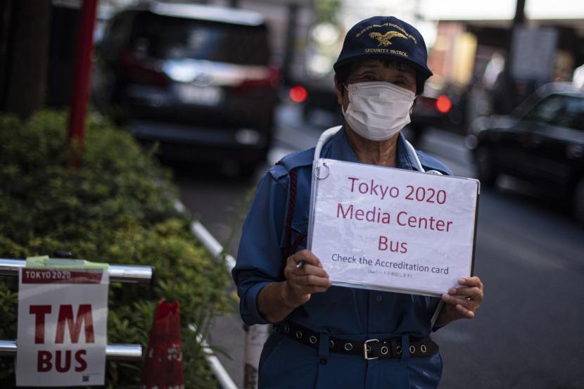 Petugas menunggu tibanya bus yang akan membawa peserta Olimpiade Tokyo 2020 di Shinjuku, Tokyo, Jepang, Rabu (21/7/2021). Para peserta Olimpiade Tokyo 2020 harus menggunakan bus atau transportasi khusus selama kegiatan olahraga tersebut berlangsung untuk menghindari kemungkinan tertularnya COVID-19.