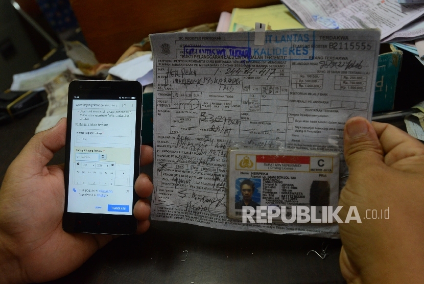  Petugas menunjukan aplikasi sidang online serta berkas tilang pelanggar lalu lintas di Kejaksaan Negeri Jakarta Barat, Jumat (29/1). (Republika/Raisan Al Farisi) 