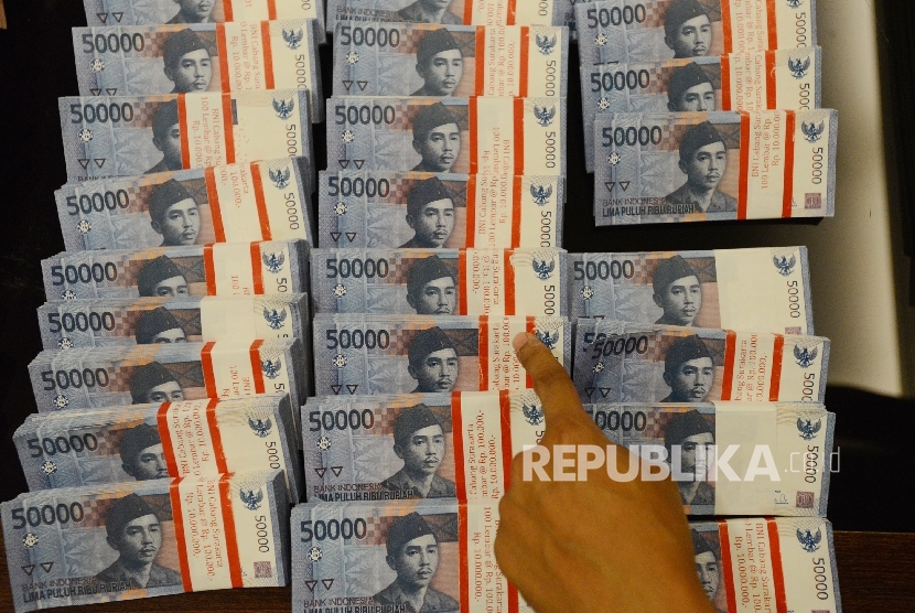 Petugas menunjukan barang bukti berupa uang palsu saat giat jumpa pers pengungkapan jaringan pengedar uang palsu di Gedung Bareskrim Polri, Jakarta, Juma (22/7). (Republika/Raisan Al Farisi)