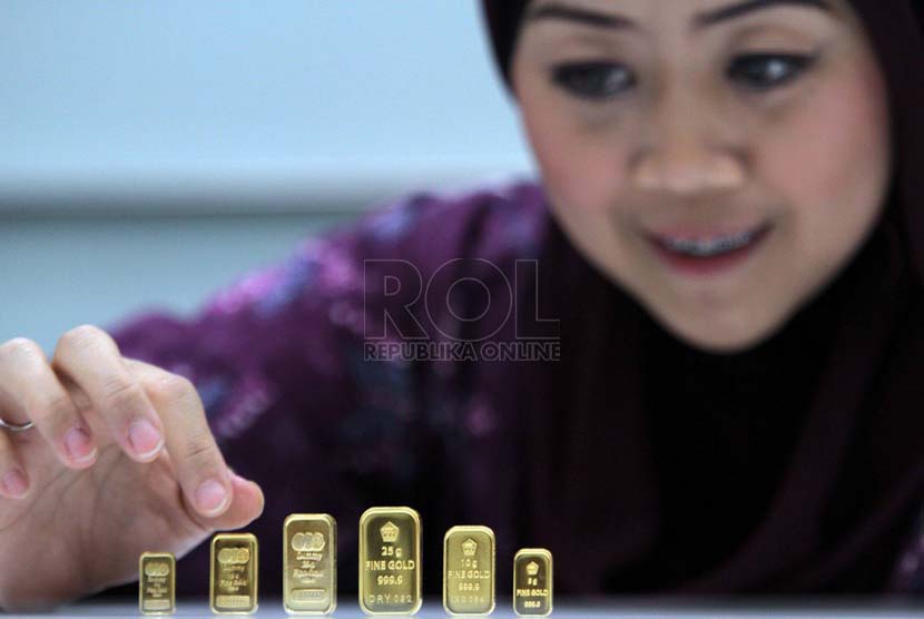  Petugas menunjukan contoh emas batangan atau logam mulia produksi Aneka Tambang di Pegadaian, Jakarta, Jumat (20/6).