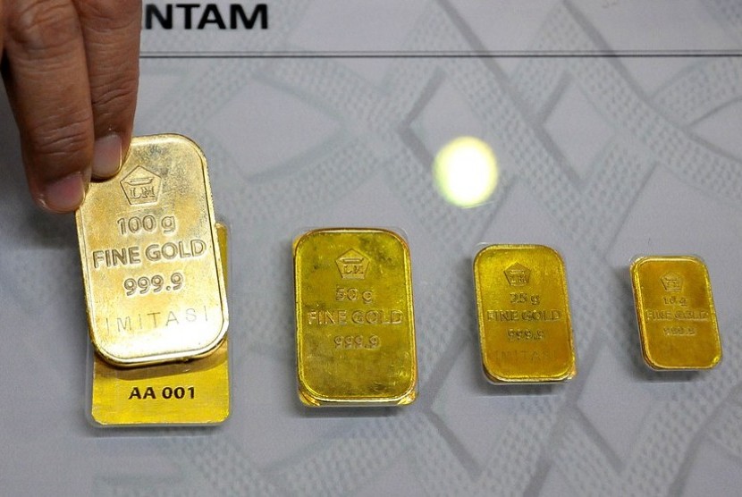 Petugas menunjukan contoh emas batangan atau logam mulia produksi PT Aneka Tambang (Antam).