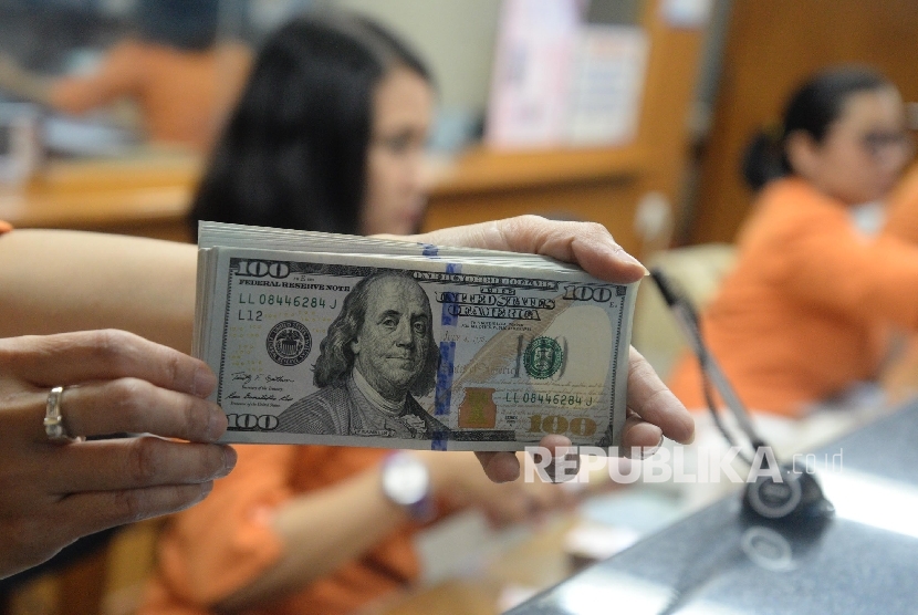  Petugas menunjukan uang dolar AS di tempat penukaran uang asing. ilustrasi