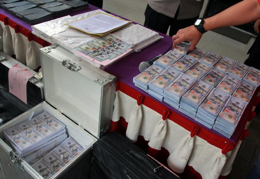 Petugas menunjukan uang dolar AS palsu pecahan 100 dolar siap edar.