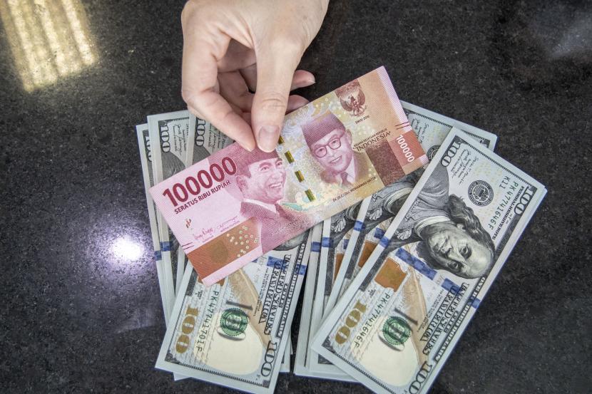 Petugas menunjukan uang pecahan Rupiah dan dolar AS di gerai penukaran mata uang asing (ilustrasi). Nilai tukar rupiah terhadap dolar Amerika Serikat (AS) terus tertekan mendekati posisi Rp 15.600.