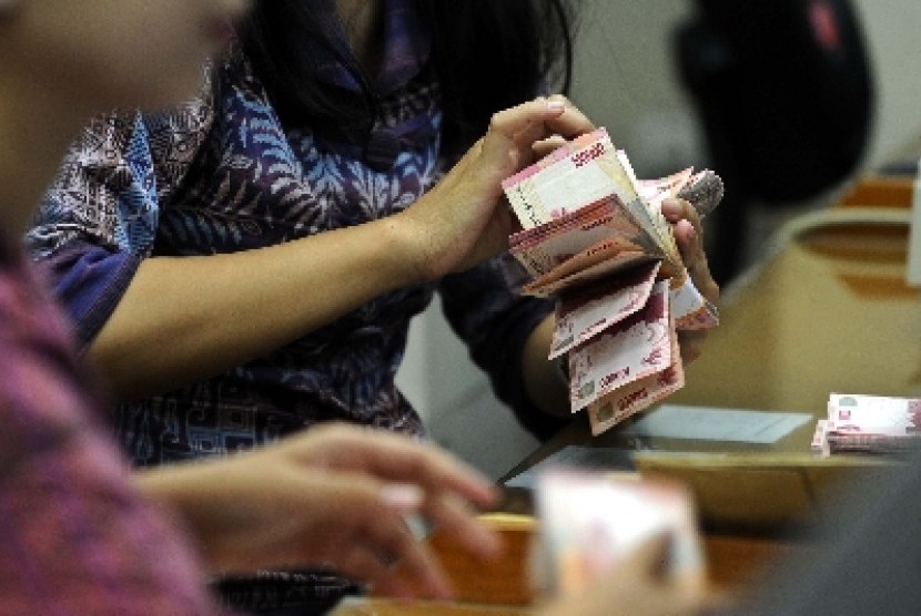  Petugas menunjukkan mata uang rupiah di tempat penukaran mata uang, Jakarta, Jumat (5/6).