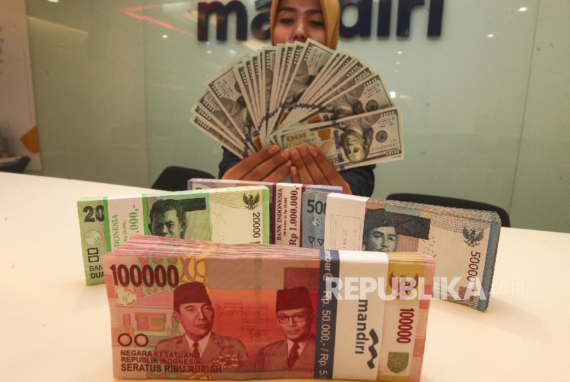 Petugas menunjukkan pecahan mata uang Dolar AS dan Rupiah di Plaza Mandiri, Jakarta.