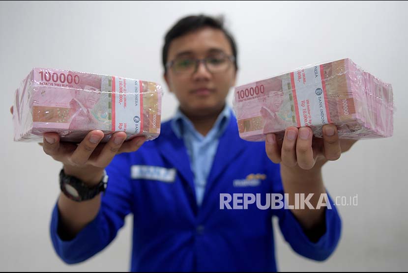 Petugas menunjukkan pecahan uang Rp100 ribu di Cash Center Bank Mandiri, Jakarta, Selasa (20/6). Bank Mandiri menyiapkan uang kartal sebesar Rp23,5 triliun untuk pengisian mesin ATM pada libur panjang lebaran, yang mana penarikan tunai melalui ATM diperkirakan meningkat menjadi Rp34,8 juta per hari dibanding tahun lalu yang hanya sebesar Rp26,7 juta per hari. 