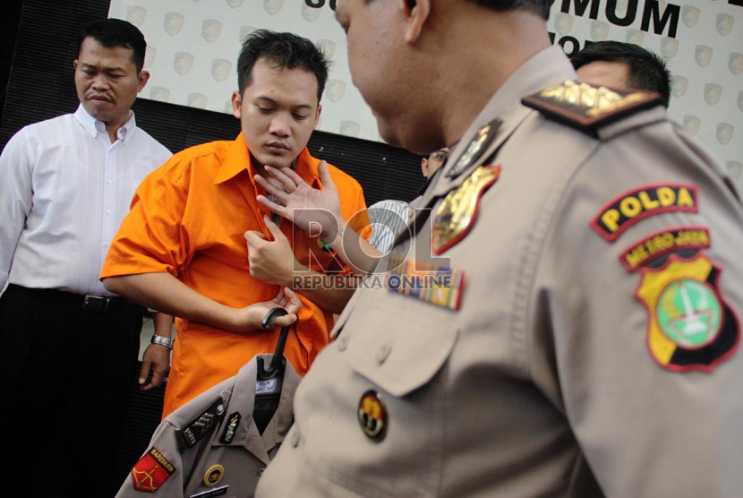   Petugas menunjukkan tersangka polisi gadungan beserta seragam dan lencana Polisi di Polda Metro Jaya, Jakarta, Kamis (25/7).  (Republika/ Yasin Habibi)