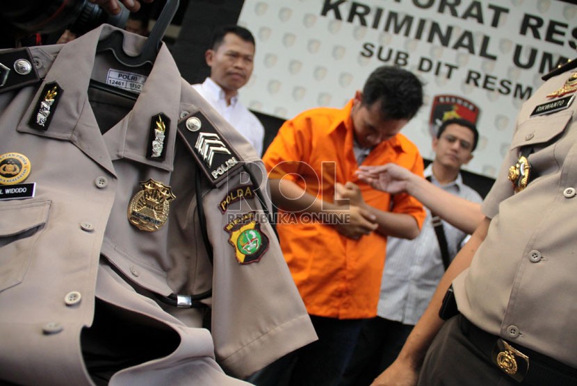   Petugas menunjukkan tersangka polisi gadungan beserta seragam dan lencana Polisi di Polda Metro Jaya, Jakarta, Kamis (25/7).  (Republika/ Yasin Habibi)