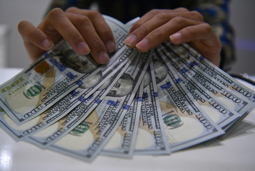 Petugas menunjukkan uang dolar Amerika Serikat di gerai penukaran mata uang bank di Jakarta. ilustrasi.
