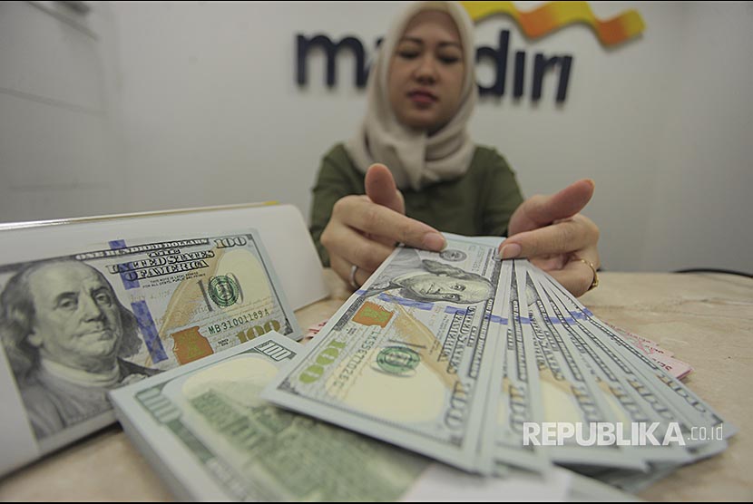 Petugas menunjukkan uang pecahan dolar AS di kantor cabang Bank Mandiri, Jakarta, Jumat (27/10). Berdasarkan data Yahoo Finance, Rupiah melemah ke level Rp13.615/USD atau tidak lebih baik dibanding sebelumnya pada  level Rp13.581/USD.  