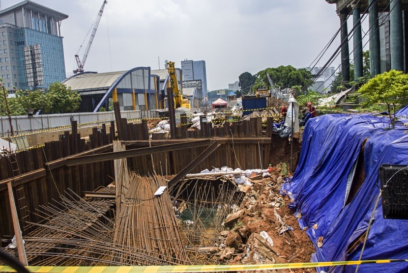 Petugas menutup dengan terpal tanah yang amblas di proyek LRT di depan Menara Saidah, Jalan MT. Haryono, Jakarta, Jumat (13/10). 
