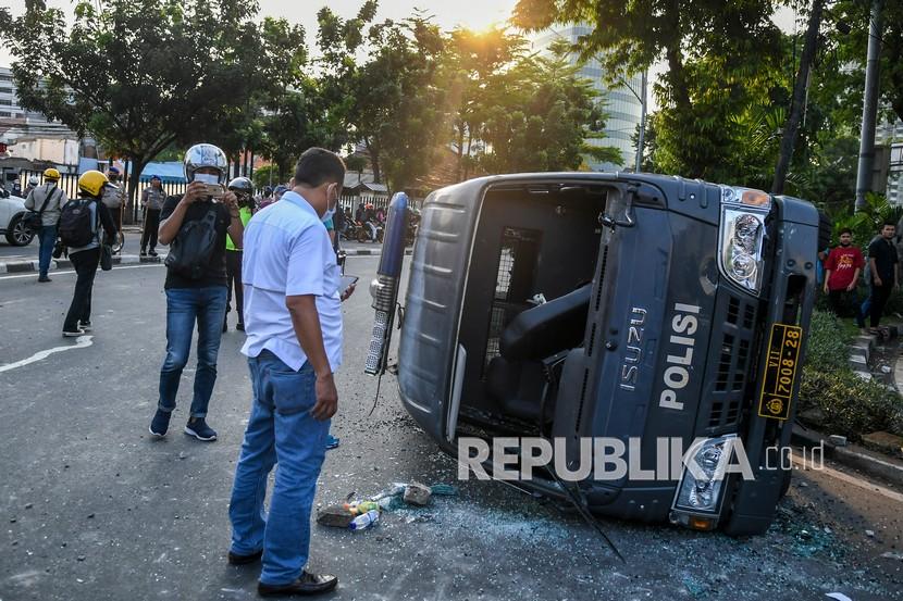 Petugas menyaksikan mobil polisi yang rusak usai bentrokan antara massa aksi tolak UU Omnibus Law Cipta Kerja dengan polisi di kawasan Penjernihan, Jakarta, Rabu (7/10/2020).