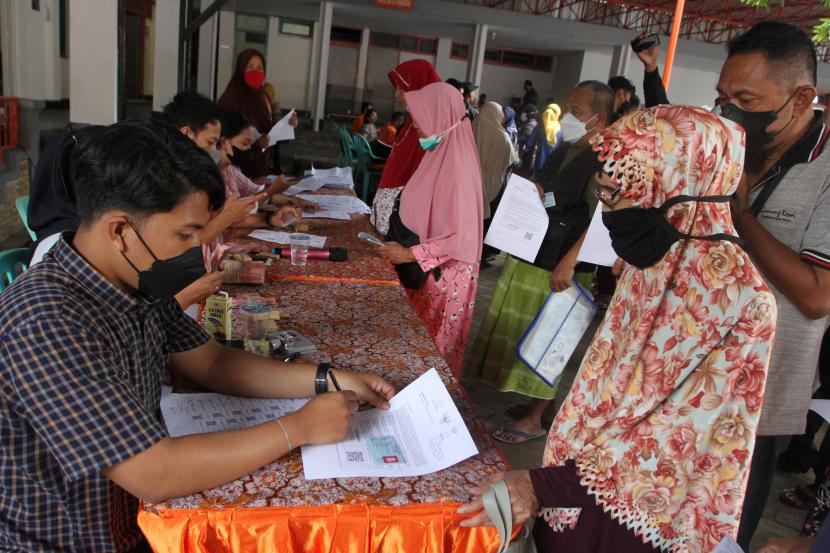 Petugas menyalurkan Bantuan Langsung Tunai (BLT) Bahan Bakar Minyak (BBM) dan Bantuan Pangan Non Tunai (BPNT) kepada seorang lansia di Kantor Pos Malang.