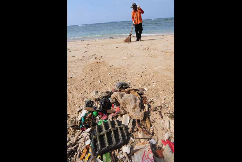 Petugas menyapu sampah-sampah yang mengotori pantai. (ilustrasi) 