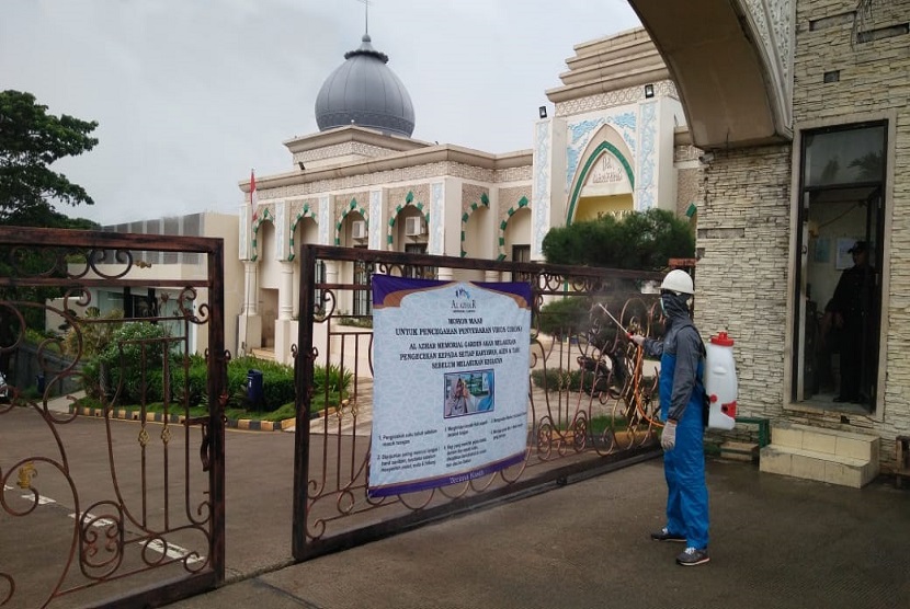 Petugas menyemprot disinfektan di depan gerbang pemakaman muslim Al Azhar Memorial Garden