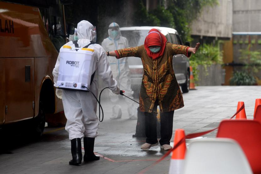 Petugas menyemprotkan cairan disinfektan kepada pasien tanpa gejala ketika baru tiba untuk melakukan isolasi mandiri.